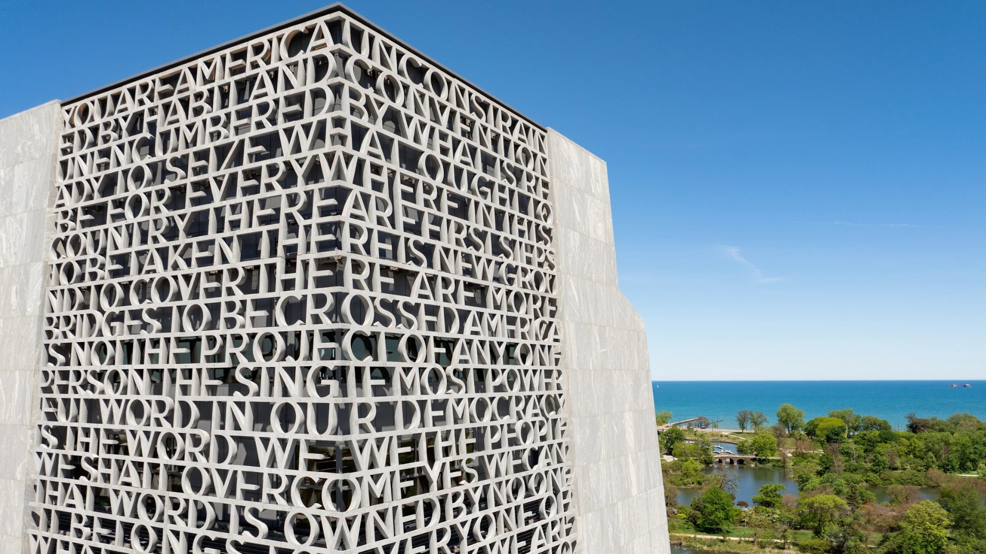 Obama Presidential Center tower in Jackson Park, Chicago, featuring carved inscriptions and a view of Lake Michigan